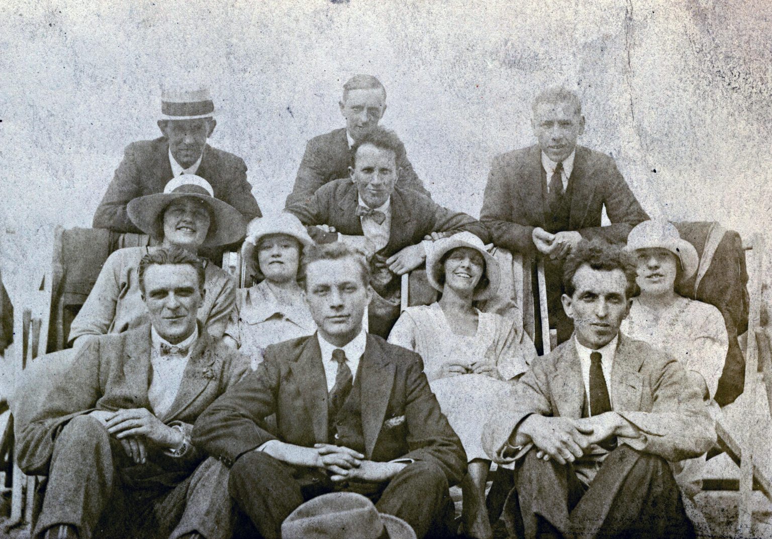 Historic black and white group photo capturing early 20th-century fashion and smiles.